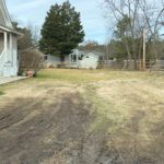 A muddy dirt driveway in need of hardscaping