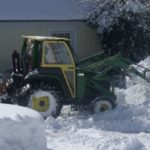 A tractor removing snow from a residential property